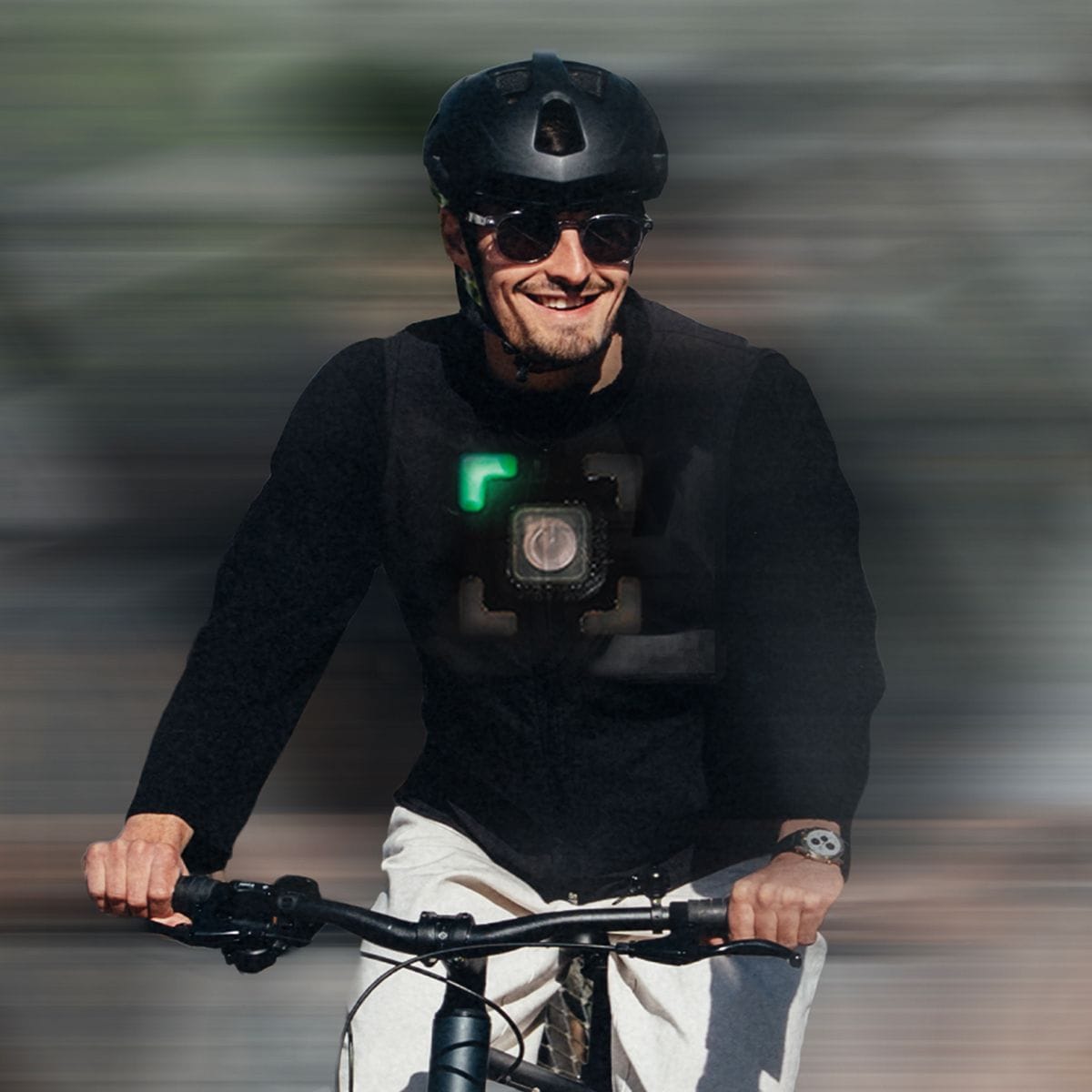 Smiling man in helmet and sunglasses cycling with a chest-mounted device.