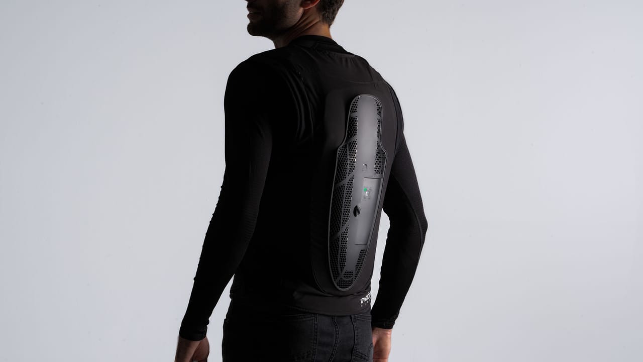 Rear view of a person wearing a black long-sleeve shirt with integrated spinal protection.