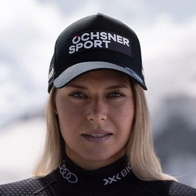 A blonde woman in a black Ochsner Sport cap and athletic wear looks directly ahead.