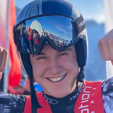 Smiling male skier in helmet and goggles flexing his biceps.