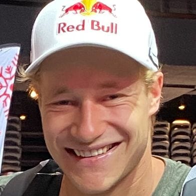 Smiling man with blonde hair wearing a white Red Bull cap.
