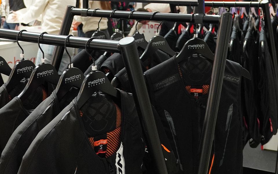 Black motorcycle jackets with orange accents hang neatly on a display rack.